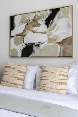 a painting above a bed with white pillows at Frank Poretr - The Pinnacle, Dubai Hills in Dubai
