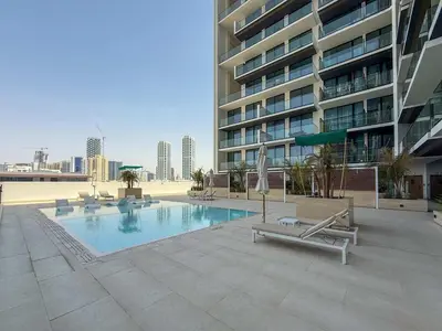 a swimming pool in front of a large building at Frank Porter - Binghatti Amber in Dubai