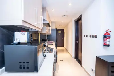 a kitchen with white cabinets and a black counter top at Elite Haven, Elegant Escape in Dubai - Free Pool in Dubai