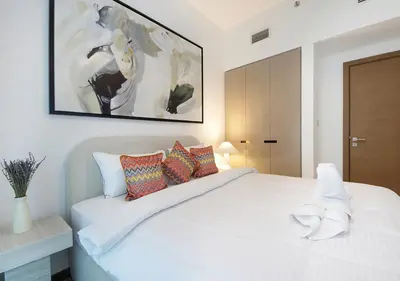 a white bedroom with a large white bed with colorful pillows at Urban Oasis 2BR Retreat in Dubai with Pool View in Dubai