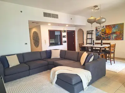 a living room with a couch and a dining room at Tratoli JBR Shared Hostel with Sea View in Dubai