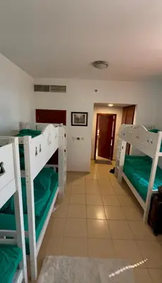 a room with three bunk beds and a hallway at Tratoli JBR Shared Hostel with Sea View in Dubai