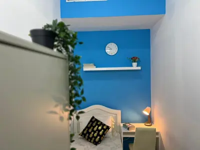 a room with a blue wall and a desk with a clock at Solo Cabin Room in Tecom Barsha Heights in Dubai