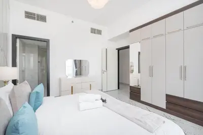 a white bedroom with a large bed with blue pillows at StayShort - Beautiful Al Furjan 2 bed apartment for 4 people in Dubai