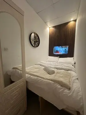 a bedroom with a bed with a mirror and a clock at Lotel Al Barsha 1 at the Mall in Dubai