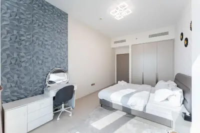a bedroom with a bed and a desk and a mirror at Grande Signature Residence by Hogar in Dubai