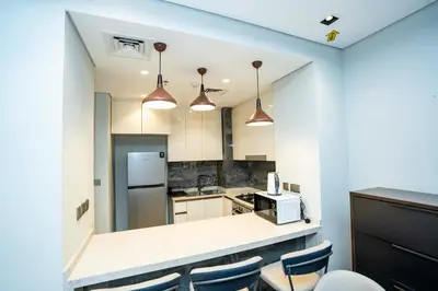 a kitchen with a counter and some blue chairs at High-Rise Comfort 2BR in Nobles Tower in Dubai in Dubai