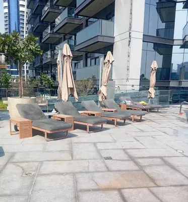 a row of lounge chairs and umbrellas in front of a building at High-Rise Comfort 2BR in Nobles Tower in Dubai in Dubai