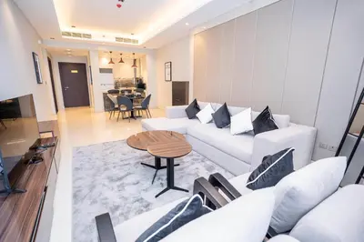 a living room with a white couch and a table at Elegant 2BR Apt Nobles Tower with Pool and Gym in Dubai