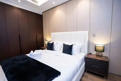 a bedroom with a large bed with white sheets and pillows at Elegant 2BR Apt Nobles Tower with Pool and Gym in Dubai