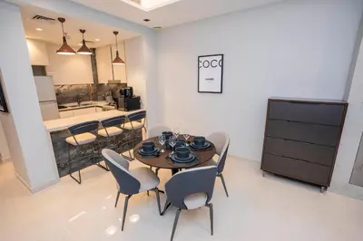 a dining room with a table and chairs and a kitchen at Elegant 2BR Apt Nobles Tower with Pool and Gym in Dubai
