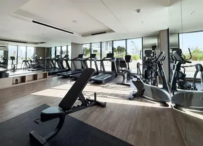 a gym with rows of treadmills and elliptical machines at Stylish 1BR Apartment in Binghatti Luna JVC Dubai in Dubai