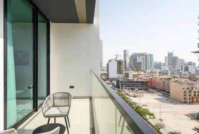 a chair on a balcony with a view of a city at Stylish Comfort Modern 1BR Apt Prime Location JVC in Dubai