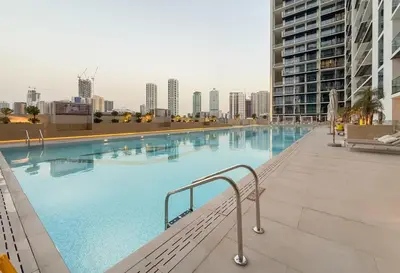 a large swimming pool with a city skyline in the background at Stylish Comfort Modern 1BR Apt Prime Location JVC in Dubai