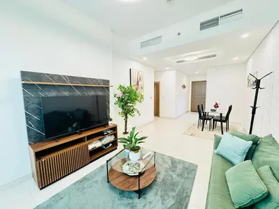 a living room with a green couch and a flat screen tv at Luxury 1BR The Bay Scenic Canal Creek Outlook in Dubai