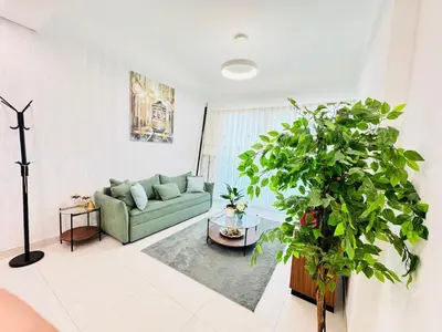 a living room with a green couch and a potted plant at Luxury 1BR The Bay Scenic Canal Creek Outlook in Dubai