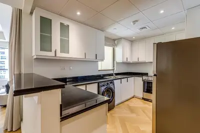 a kitchen with white cabinets and a black refrigerator at Rimal 1 in JBR - 1 Bedroom Apartment - Allsopp & Allsopp in Dubai