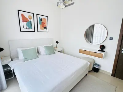 a white bedroom with a white bed and a mirror at Cozy 1br in Sobha Creek Vistas Creek Sea View in Dubai