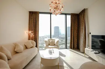 a living room with a couch and a chandelier at SOBHA Hartland Grande 1 BHK in Dubai
