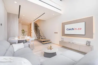 a living room with white furniture and a staircase at Chic Duplex 1BHK by CzechIn Luxe Stay with Pool Gym in Dubai