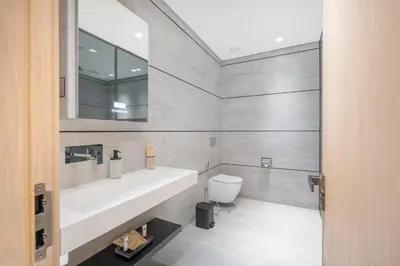 a bathroom with a sink and a toilet and a mirror at Chic Duplex 1BHK by CzechIn Luxe Stay with Pool Gym in Dubai