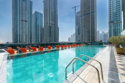 a large swimming pool with orange chairs and buildings at MBL Lake VIEW 1 BR in Dubai