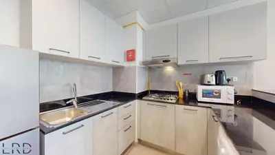 a kitchen with white cabinets and a sink at Chic & Cozy 1BR in Centurion Onyx in Dubai