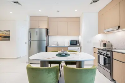 a kitchen with a table and two green chairs at Lux Creek Home with Burj View steps from the Lagoon in Dubai