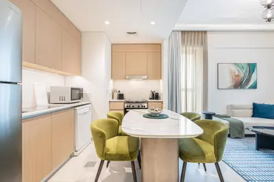 a kitchen and living room with a table and chairs at Lux Creek Home with Burj View steps from the Lagoon in Dubai