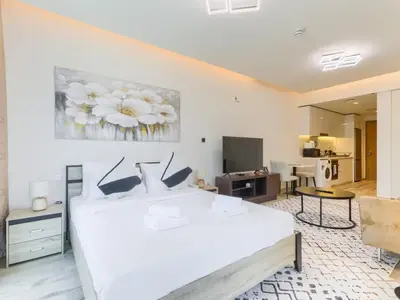 a bedroom with a white bed and a living room at TRPS - Ahad Residences, Business Bay - Full Burj Khalifa View - Modern Furnished Studio in Dubai
