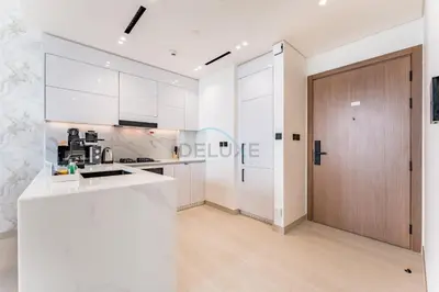 a kitchen with white cabinets and a wooden door at Sky Level 1BR with Lake View and City Glimpse, Close Proximity to Community Park, Binghatti Onyx, Jumeirah Village Circle by Deluxe Holiday Homes in Dubai