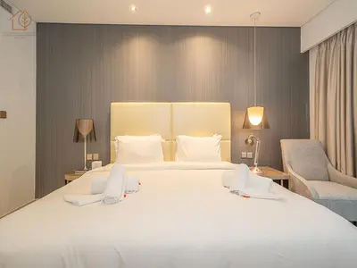 a bedroom with a large white bed and two chairs at Elegant 2 Bedroom Apartment with Pool Views at Business Bay 211DPA-2 in Dubai