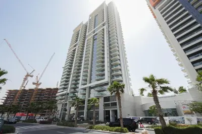 a tall white building with construction cranes at Keyrock Golf Gate - Damac Hills Apartment with Pool, Gym & Free Parking in Dubai