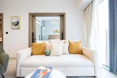 a living room with a white couch and yellow pillows at Keyrock Golf Gate - Damac Hills Apartment with Pool, Gym & Free Parking in Dubai