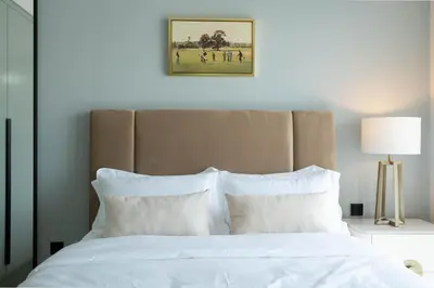 a bed with white pillows and a picture on the wall at KeyRock Golf Gate - Stylish Retreat with Pool and Gym in Dubai
