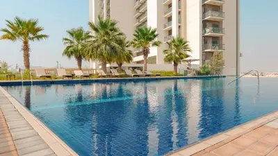 a swimming pool with palm trees and a building at KeyRock Golf Gate - Stylish Retreat with Pool and Gym in Dubai