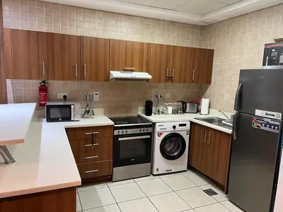 a kitchen with a refrigerator and a washing machine at Stylish 1 bedroom apartment with full kitchen in Dubai