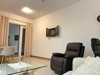 a living room with a couch and a clock on the wall at Stylish 1 bedroom apartment with full kitchen in Dubai