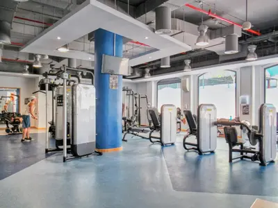 a gym with cardio machines and a woman in the background at Modern & Spacious Studio in JBR in Dubai