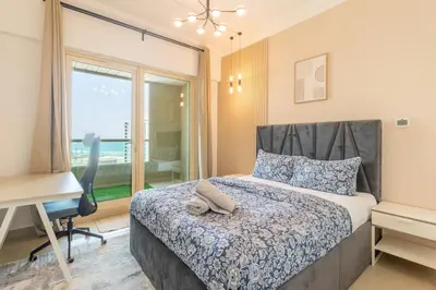 a bedroom with a bed and a desk and a window at Luxury 3BR in Dubai Marina Man 2203 in Dubai