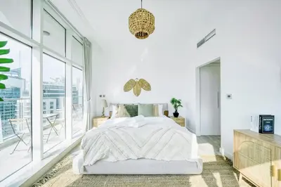 a white bedroom with a bed and a large window at Cozy and Spacious 2Bedroom with Marina Bay view in Dubai