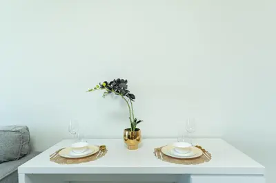 a table with two plates and a vase with flowers at PVH - Modern 1BR Near Metro - Alexis Tower in Dubai