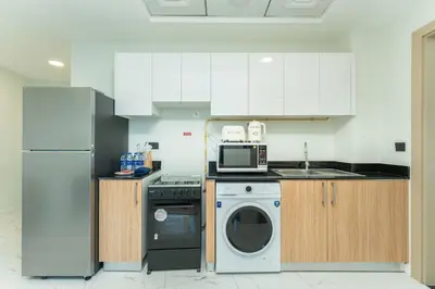 a kitchen with a washing machine and a microwave at PVH - Modern 1BR Near Metro - Alexis Tower in Dubai
