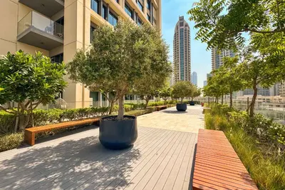 a park with trees and benches in a city at PVH - Canal View 1BR - Burj Royale in Dubai