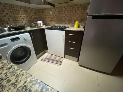 a kitchen with a washing machine and a sink at Studio with homely cozy and positive vibes in Sabkhah
