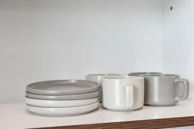 a group of plates and cups on a shelf at Modern 1 Bedroom Apartment in Damac Hills 2 in Dubai