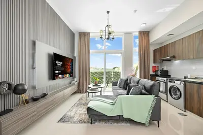 a living room with a couch and a kitchen at Modern 1 Bedroom Apartment in Damac Hills 2 in Dubai