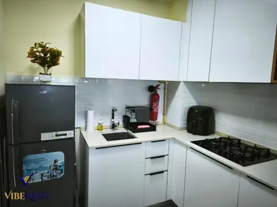 a kitchen with white cabinets and a black refrigerator at Modern 1BR Apartment with Pool & Gym, 15 Min to JBR in Dubai
