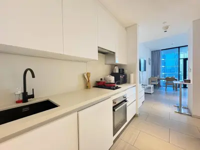 a kitchen with white cabinets and a large window at Spacious Studio Private Balcony Sea View in Dubai