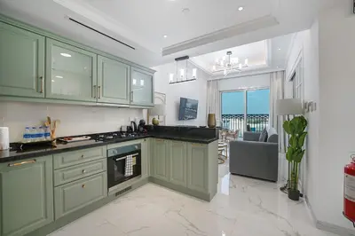 a kitchen with green cabinets and a view of the ocean at EasyGo- Luxury Living with Resort Facilities and Amenities in Dubai